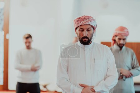 Photo for A group of Muslims in a modern mosque praying the Muslim prayer namaz, during the holy month of Ramadan. - Royalty Free Image