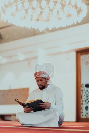 Photo for A Muslim reads the holy Islamic book Quraqn in a modern grand mosque during the Muslim holy month of Ranazan. - Royalty Free Image
