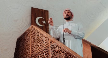 Foto de Musulmanes imán árabe tiene un discurso el viernes por la tarde la oración en la mezquita. Los musulmanes se han reunido para la oración del viernes por la tarde en la mezquita y están escuchando el discurso del imán. - Imagen libre de derechos