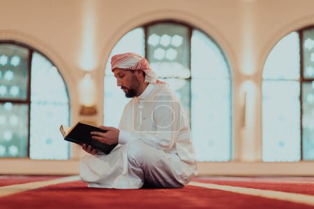 Foto de Un musulmán lee el libro sagrado islámico Quraqn en una mezquita moderna durante el mes sagrado musulmán de Ranazán. - Imagen libre de derechos