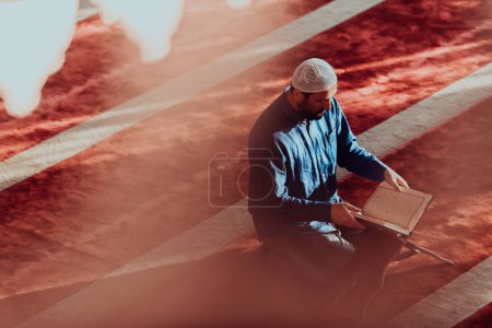 Photo for A Muslim reads the holy Islamic book Quraqn in a modern grand mosque during the Muslim holy month of Ranazan. - Royalty Free Image