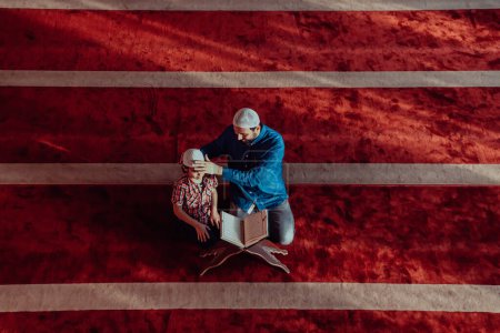 Photo for Muslim prayer father and son in mosque praying and reading holly book Quran together islamic education concept. - Royalty Free Image