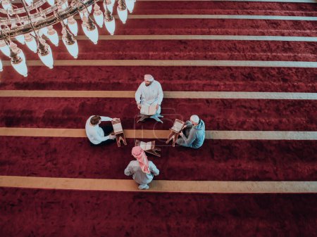 Téléchargez les photos : Un groupe de musulmans lisant le livre sacré du Coran dans une mosquée moderne pendant la fête musulmane du Ramadan. - en image libre de droit