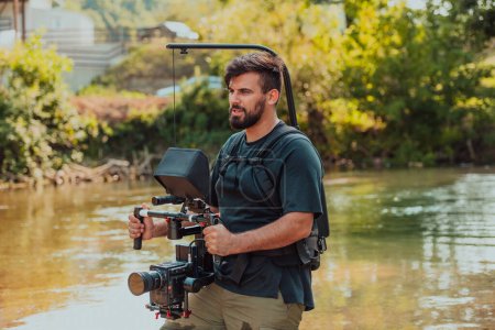 Téléchargez les photos : A professionally equipped cameraman shoots in the water surrounded by beautiful nature. High quality photo - en image libre de droit