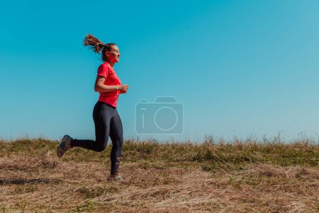Photo for Young happy woman enjoying in a healthy lifestyle while jogging on a country road through the beautiful sunny forest, exercise and fitness concept. - Royalty Free Image
