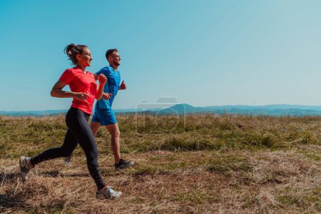 Couple enjoying in a healthy lifestyle while jogging on a country road through the beautiful sunny forest, exercise and fitness concept. 