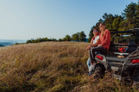Foto de Young happy excited couple enjoying beautiful sunny day while driving a off road buggy car on mountain nature. - Imagen libre de derechos