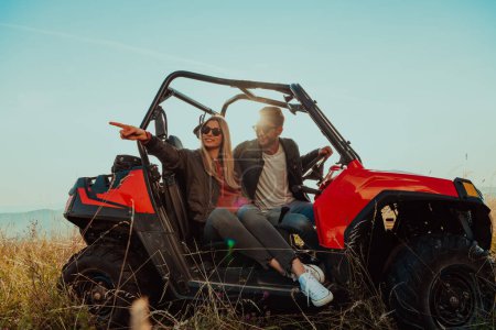 Téléchargez les photos : Young happy excited couple enjoying beautiful sunny day while driving a off road buggy car on mountain nature. - en image libre de droit