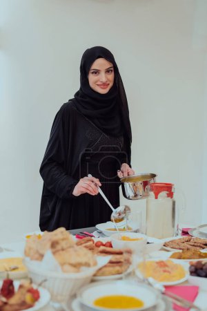 Photo for Young Muslim woman serving food for iftar during Ramadan. - Royalty Free Image
