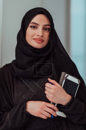 Téléchargez les photos : Young modern muslim business woman using tablet wearing traditional hijab clothes at home. - en image libre de droit
