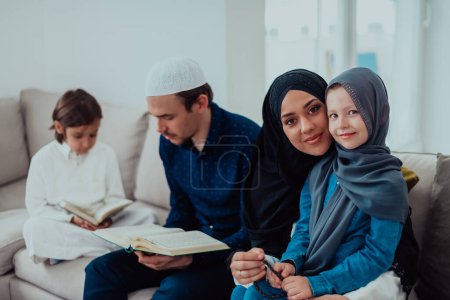Téléchargez les photos : Happy Muslim family enjoying the holy month of Ramadan while praying and reading the Quran together in a modern home. - en image libre de droit