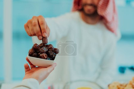 Téléchargez les photos : Famille musulmane multiethnique moderne partageant un bol de dates tout en profitant iftar dîner ensemble lors d'un festin de ramadan à la maison
. - en image libre de droit