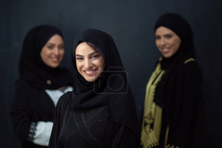 Foto de Group portrait of beautiful Muslim women in a fashionable dress with hijab isolated on black background. - Imagen libre de derechos