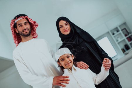 Photo for Portrait of young happy arabian muslim family couple with son in traditional clothes spending time together during the month of Ramadan at home. High quality photo - Royalty Free Image