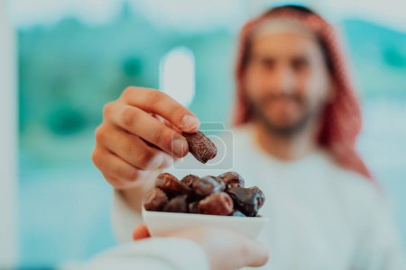 Photo for Modern multiethnic muslim family sharing a bowl of dates while enjoying iftar dinner together during a ramadan feast at home. - Royalty Free Image