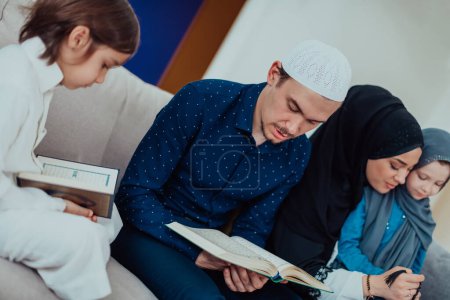 Foto de Happy Muslim family enjoying the holy month of Ramadan while praying and reading the Quran together in a modern home. - Imagen libre de derechos