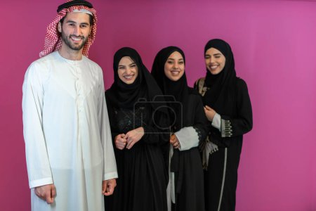 Téléchargez les photos : Group portrait of young Muslim people Arabian men with three Muslim women in a fashionable dress with hijab isolated on a pink background. - en image libre de droit