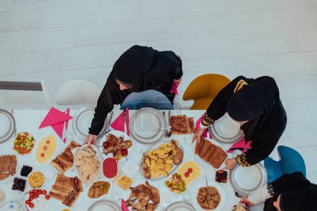 Téléchargez les photos : Top view of Muslim family having Iftar dinner drinking water to break feast. Eating traditional food during Ramadan feasting month at home. The Islamic Halal Eating and Drinking in modern home. - en image libre de droit