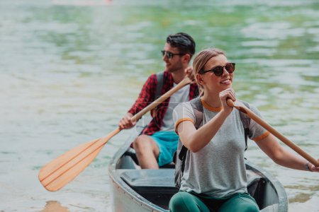 Téléchargez les photos : Quelques amis explorateurs aventureux font du canoë dans une rivière sauvage entourée par la belle nature. - en image libre de droit