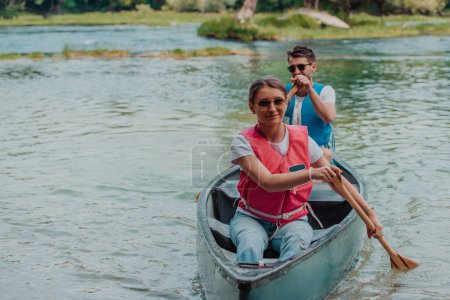 Foto de Pareja aventureros exploradores amigos están navegando en canoa en un río salvaje rodeado de la hermosa naturaleza. - Imagen libre de derechos