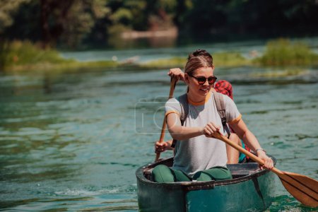 Photo for Couple adventurous explorer friends are canoeing in a wild river surrounded by the beautiful nature. - Royalty Free Image