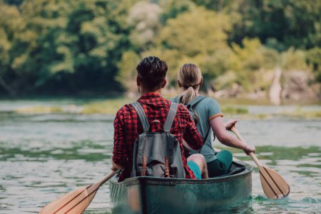 Téléchargez les photos : Quelques amis explorateurs aventureux font du canoë dans une rivière sauvage entourée par la belle nature. - en image libre de droit
