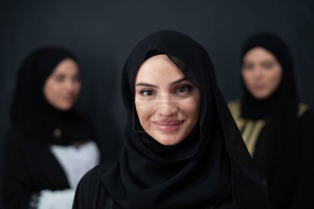 Téléchargez les photos : Group portrait of beautiful Muslim women in a fashionable dress with hijab isolated on black background. - en image libre de droit