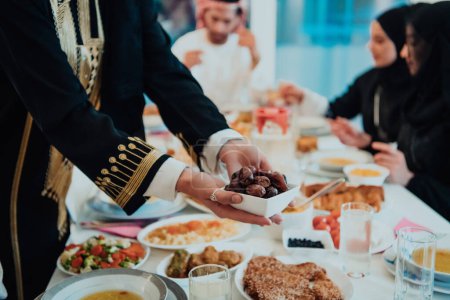Photo for Muslim family having Iftar dinner drinking water to break feast. Eating traditional food during Ramadan feasting month at home. The Islamic Halal Eating and Drinking in modern home. - Royalty Free Image