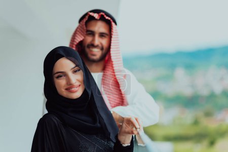 Photo for Portrait of young arabian muslim couple in traditional clothes standing on balcony representing modern islam fashion and ramadan kareem concept. - Royalty Free Image
