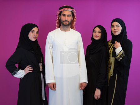Téléchargez les photos : Portrait de groupe de jeunes musulmans homme arabe avec trois femmes musulmanes en robe à la mode avec hijab isolé sur fond rose représentant la mode islam moderne et concept de Ramadan Kareem
. - en image libre de droit