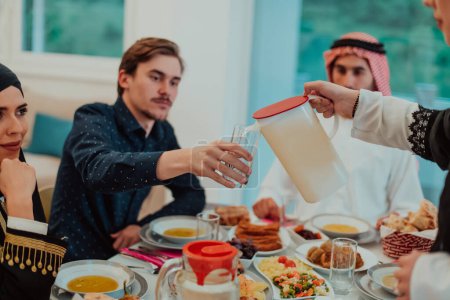 Téléchargez les photos : Muslim family having Iftar dinner drinking water to break feast. Eating traditional food during Ramadan feasting month at home. The Islamic Halal Eating and Drinking in modern home. - en image libre de droit
