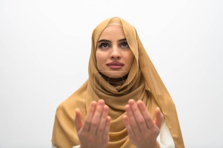 Foto de Portrait of beautiful muslim woman in fashionable dress with hijab making traditional prayer to God keeps hands in praying gesture isolated on white background. - Imagen libre de derechos