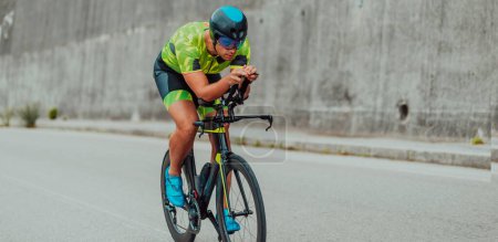 Foto de Full length portrait of an active triathlete in sportswear and with a protective helmet riding a bicycle. Selective focus . - Imagen libre de derechos