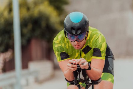 Foto de Active triathlete in sportswear and with a protective helmet riding a bicycle. Selective focus . - Imagen libre de derechos