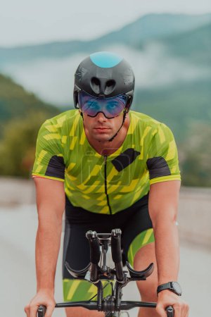Photo for Active triathlete in sportswear and with a protective helmet riding a bicycle. Selective focus . - Royalty Free Image