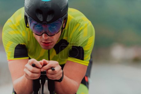 Téléchargez les photos : Close up photo of an active triathlete in sportswear and with a protective helmet riding a bicycle. Selective focus. - en image libre de droit