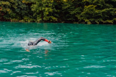 Foto de A triathlete in a professional swimming suit trains on the river while preparing for Olympic swimming. - Imagen libre de derechos