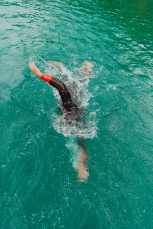 Foto de A triathlete in a professional swimming suit trains on the river while preparing for Olympic swimming. - Imagen libre de derechos