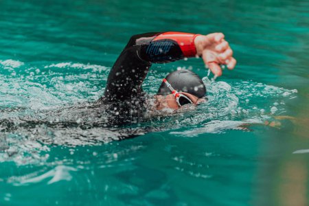 Téléchargez les photos : A triathlete in a professional swimming suit trains on the river while preparing for Olympic swimming. - en image libre de droit