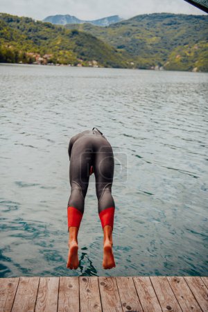 Photo for Triathlon athlete jumping in water and starting with training. - Royalty Free Image