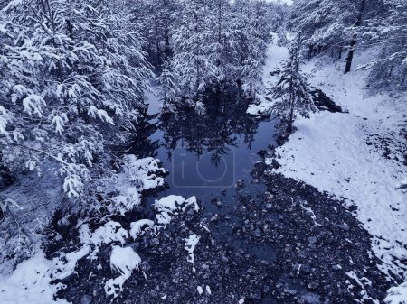 Téléchargez les photos : An aerial view of a frozen river flowing through snow-covered forests on a cloudy sunset sky background. Hi quality 4K footage. - en image libre de droit