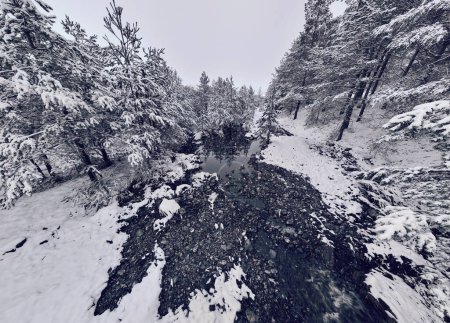 Foto de An aerial view of a frozen river flowing through snow-covered forests on a cloudy sunset sky background. Hi quality 4K footage. - Imagen libre de derechos