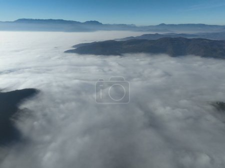 Foto de Aerial View. Flying over the high mountains in beautiful clouds. Aerial Drone camera shot. Air pollution clouds over Sarajevo in Bosnia and Herzegovina. Hi quality 4K footage. - Imagen libre de derechos