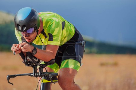 Photo for Close up photo of an active triathlete in sportswear and with a protective helmet riding a bicycle. Selective focus. - Royalty Free Image