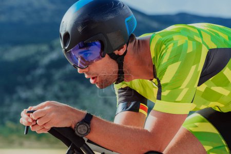 Photo for Close up photo of an active triathlete in sportswear and with a protective helmet riding a bicycle. Selective focus. - Royalty Free Image