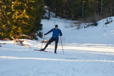 Téléchargez les photos : Nordic skiing or Cross-country skiing classic technique practiced by man in a beautiful panoramic trail at morning. Selective focus - en image libre de droit
