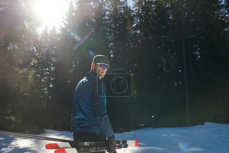 Téléchargez les photos : Portrait handsome male athlete with cross country skis in hands and goggles, training in snowy forest. Healthy winter lifestyle concept - en image libre de droit