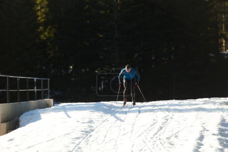 Téléchargez les photos : Ski nordique ou ski de fond technique classique pratiquée par l'homme dans un magnifique sentier panoramique le matin. Concentration sélective - en image libre de droit
