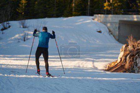 Foto de Esquí nórdico o esquí de fondo técnica clásica practicada por el hombre en un hermoso sendero panorámico por la mañana. Enfoque selectivo - Imagen libre de derechos