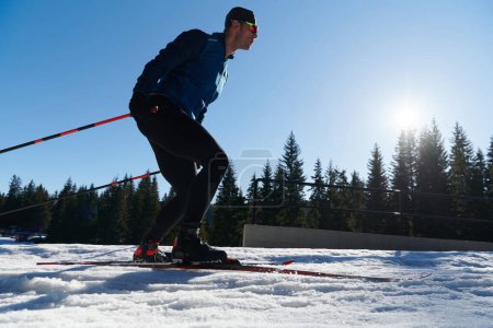 Téléchargez les photos : Nordic skiing or Cross-country skiing classic technique practiced by man in a beautiful panoramic trail at morning. Selective focus - en image libre de droit
